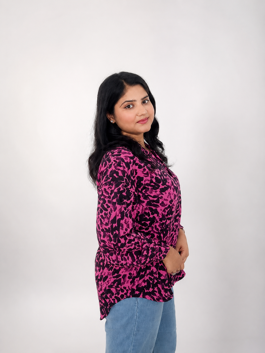 Woman wearing a pink and black patterned top against a white background